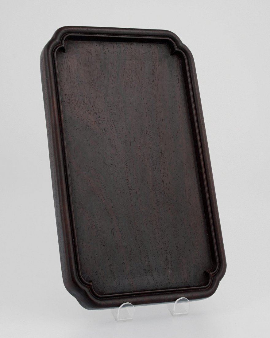 A ZITAN WOOD TRAY, POST-REPUBLICAN PERIOD,: A ZITAN WOOD TRAY POST-REPUBLICAN PERIOD the flat inkstone smoothly carved in chestnut-red zitan wood with indented corners and a raised border, 11.4" x 6.7" — 29 x 17 cm. Estimate $40