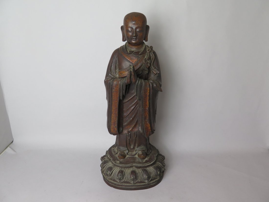 Chinese lacquered bronze luohan Early Ming Dyna: Early Ming DYNASTY..Standing on a lotus base with a meditative expression.dressed in simple gilt and brown lacquered long robe.H: 37.5cm