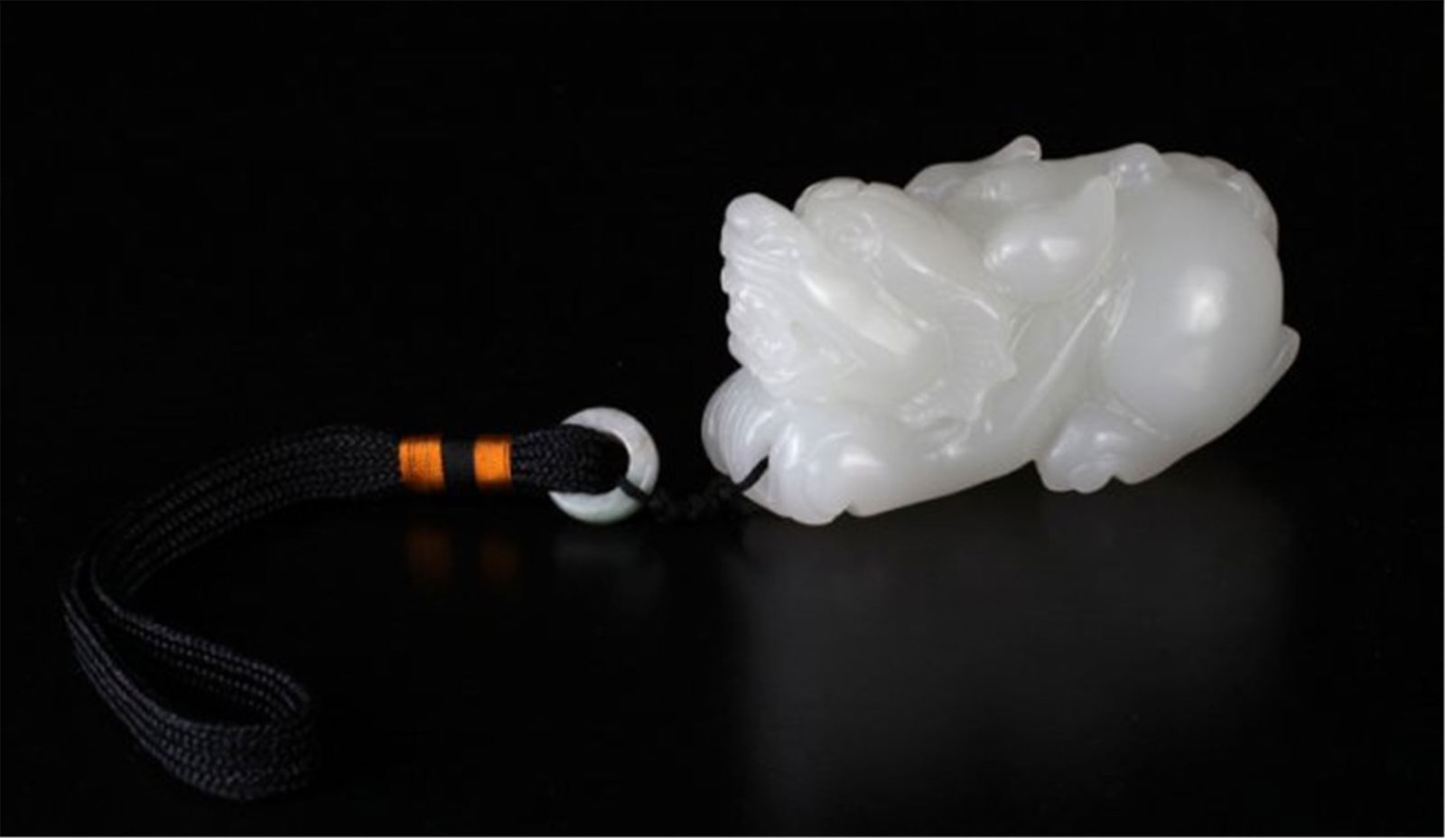 chinese jade foo lion: Depicting a three-dimensional foo lion attached to cord with jadeite bead. Foo lion measures 1.75"""" H x 3.125"""" L x 1.5"""" W."""