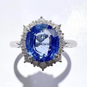 SAPPHIRE AND DIAMOND OVAL CLUSTER RING WITH FLORAL HALO DESIGN (20TH CENTURY): SAPPHIRE AND DIAMOND OVAL CLUSTER RING WITH FLORAL HALO DESIGN (20TH CENTURY) Provenance and Authenticity: This elegant ring features a prominent oval-shaped blue sapphire surrounded by a finely craft