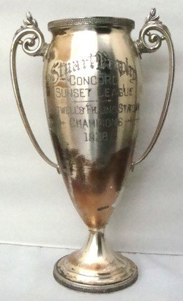 1938 Baseball Trophy, Wallace: 1938 Baseball Trophy with baseball player lid; two-handled with engraved front: 'Stuart Trophy. Concord Sunset League, Boutwell's Filling Station 1938'; measures approx 20" tall and 4" in diameter at 