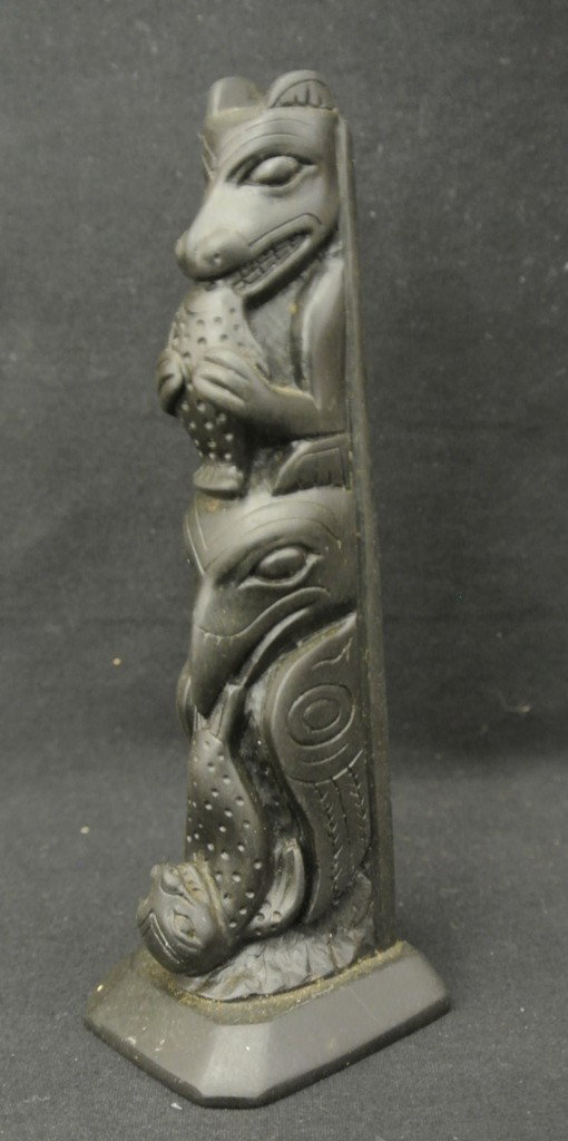 North West Carved Argillite Totem Pole: North West Carved Argillite Totem Pole. This 5 ½” high totem pole features a bear, salmon, eagle and seal totem. It is marked “JW # 1165 ARG Made in BC” on the botto