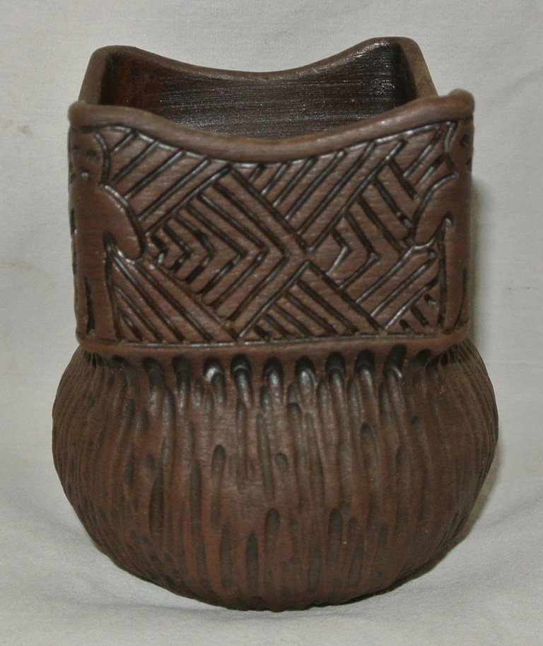 Iroquois Pottery Jar with Square Top: Iroquois Pottery Jar with Square Top. Carved designs on outside including 4 humans-one at each corner. Measures 4.5” high x 4” in diameter. Signed in Iroquois on bottom along with feather, turtle 