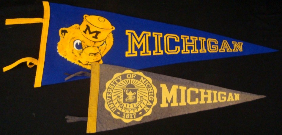 Pair of University of Michigan Pennants: Pair of University of Michigan Pennants; features vintage 3/4 length pennant in VG+ condition - measures approx 21" in length - faded blue felt pennant with yellow lettering and piping - features Univ