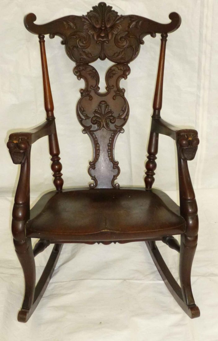 Mahogany Carved Freemason Symbolism Rocking Chair: Ornately carved rocking chair, Devilish face on back, lion head handles with triple cross on shield in open mouth, underneath is a paper label with an MS intertwined with a Knights Templar Sword throu