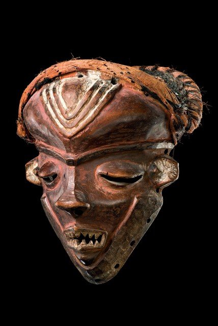 Mask "mbuya" - D. R. Congo, Pende: wood, polychrome paint, marked by continous brows, eyes with hanging lids and the typical "snub nose", scarification marks "mifunyi" on forehead and cheeks, raffia bast bonnet, min. dam., cracks, slig