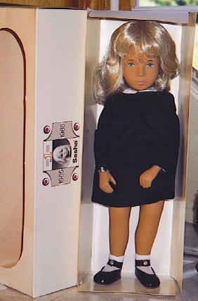46_16" Sasha in Navy Blue, Made in England: Blonde, blue eye Sasha in navy blue corduroy dress, white socks and center snap shoes, complete with wrist tag and windowpane box marked on side "No 1 – Sasha 1965 – 1985". Specialty issue Sasha i