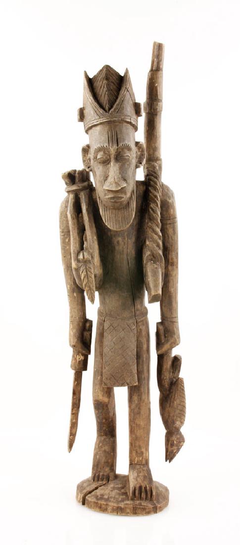 African Warrior Figure: African figure, carved wood, depicting a man carrying weapons and animals, 30" high.