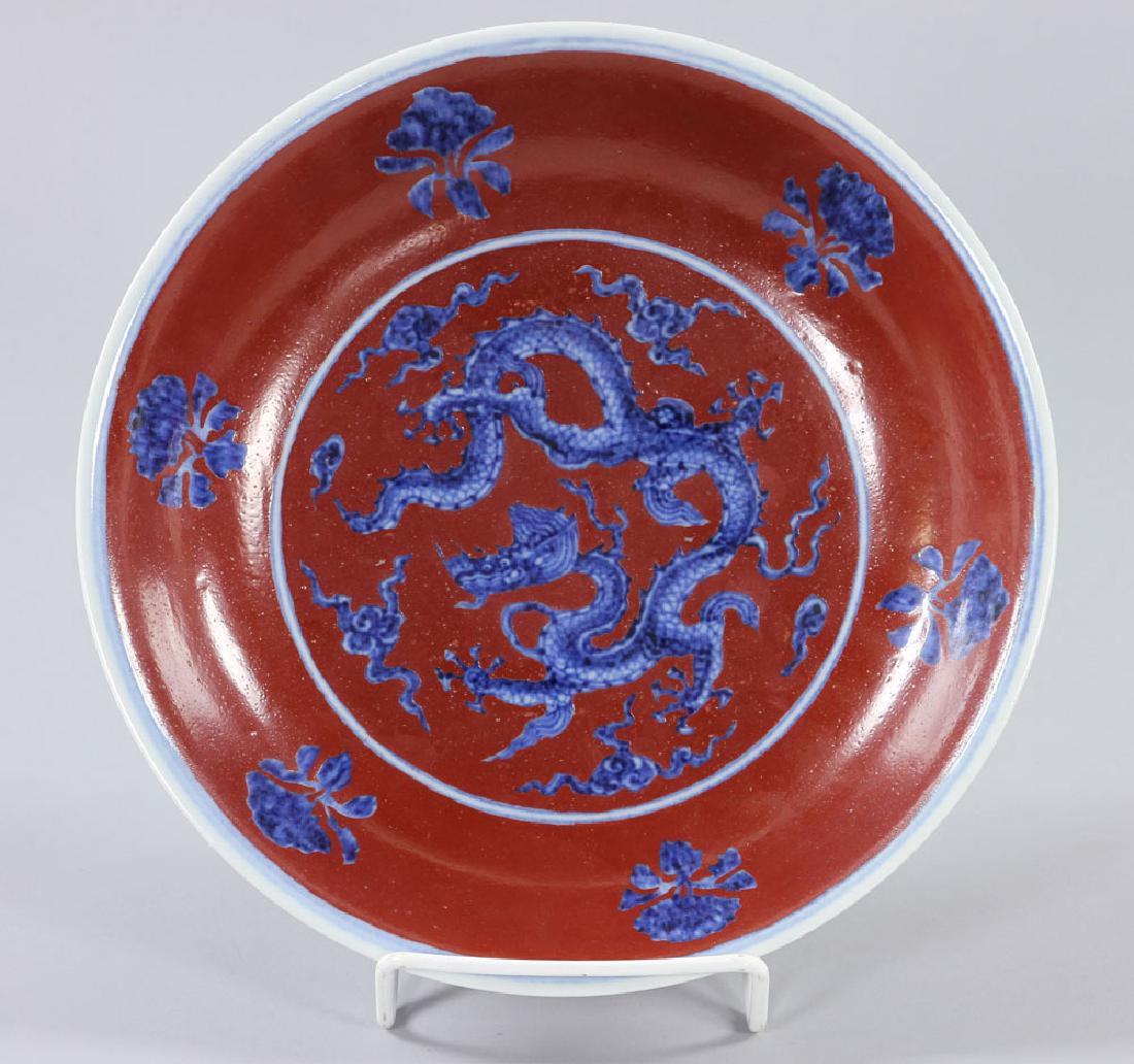 Chinese Copper Red with Underglaze Blue and White Plate: Chinese copper red porcelain plate, with underglaze blue and white dragon motif, Hongzhi mark on base, 9 1/2" dia. Provenance: From a private Massachusetts estate.