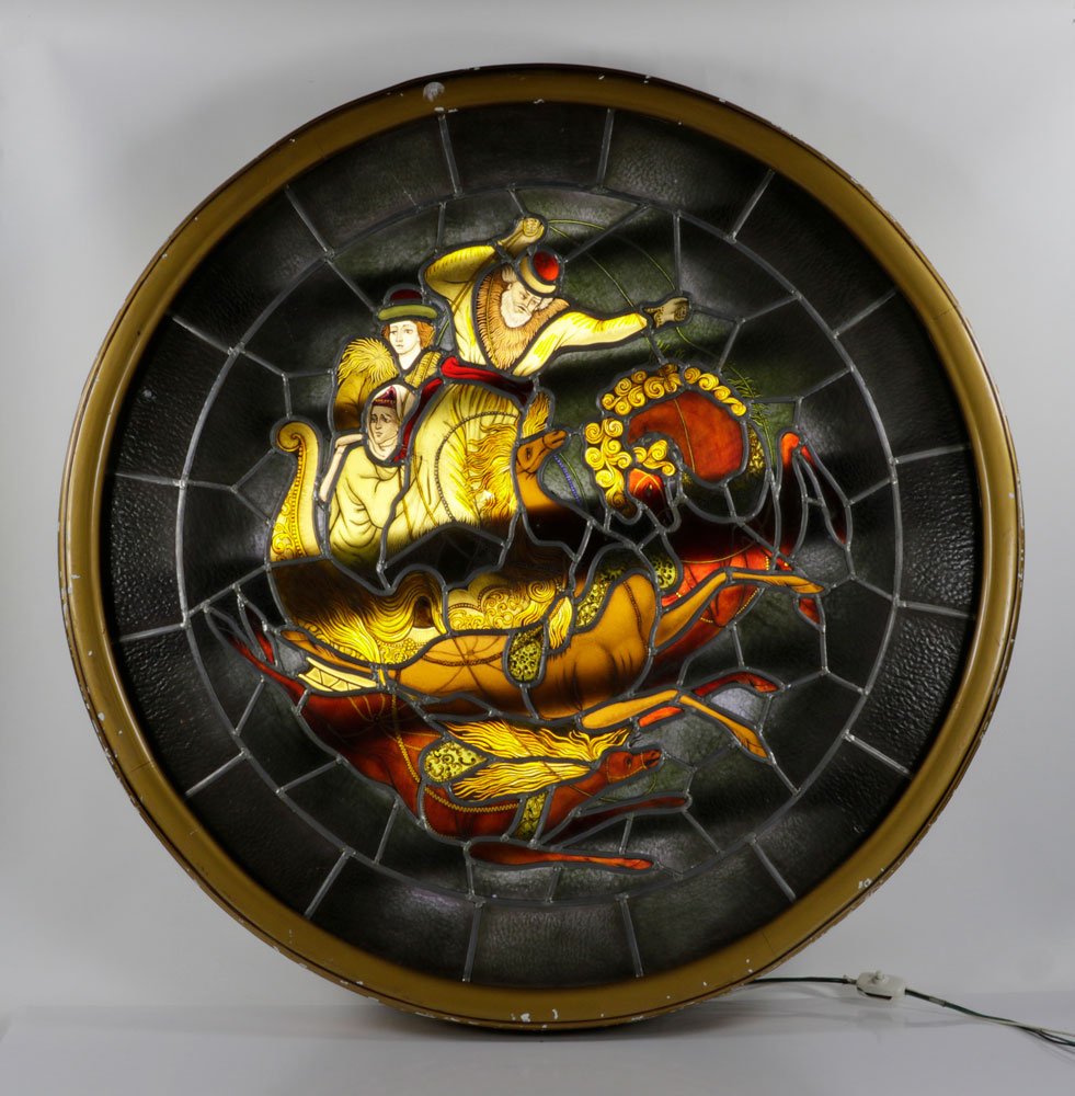 Early 20th C. Stained Leaded Glass Window: Stained leaded glass window, circa 1900, with figural decoration, in lit shadow box frame, 43" dia (frame); cord partially cut and needs rewired to operate, two pieces of glass with cracks. The absenc