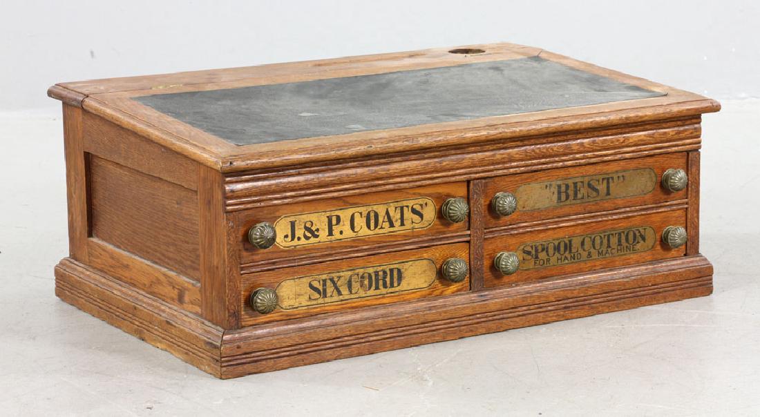J. & P. Coats Oak Spool Cabinet: J. & P. Coats oak spool cabinet, leather-topped slant lid above four short drawers with metal pulls, marked "J. & P. Coats, Best Six Cords, 200 Yds, 50, Spool Cotton" measuring 12" h x 29 3/4" w x 20 