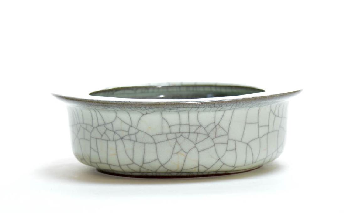 Chinese Crackle Dish: Chinese crackle dish, the rounded sides rising from a short tapered foot to a lipped rim, applied overall with a soft, creamy grey glaze suffused with a matrix of dark and golden crackles. Unglazed fo