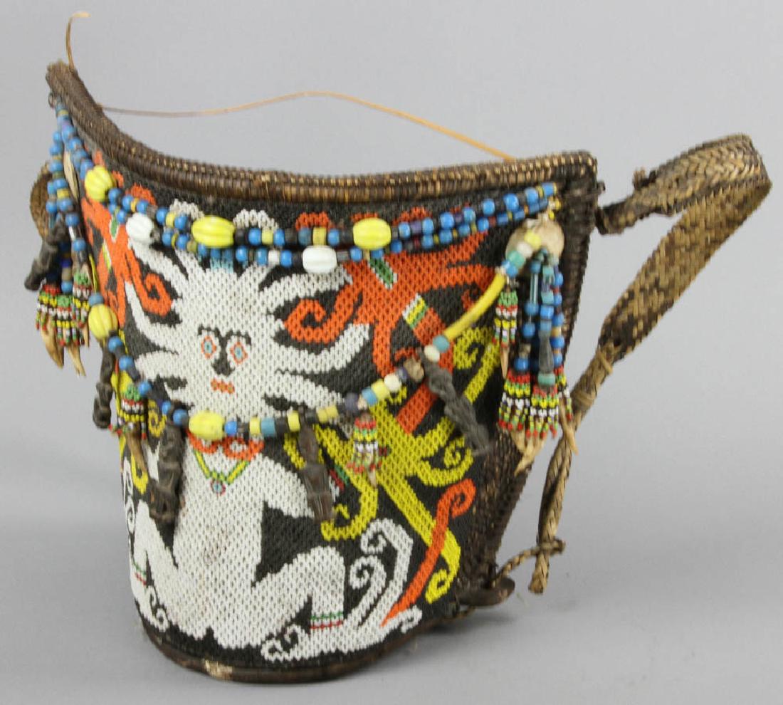 Borneo Indonesia Baby Carrier: Borneo, Indonesia baby carrier, decorated with shell discs, crocodile teeth, and melon beads. The baby is not named or allowed to touch the ground until it is three months old; the decorations protect