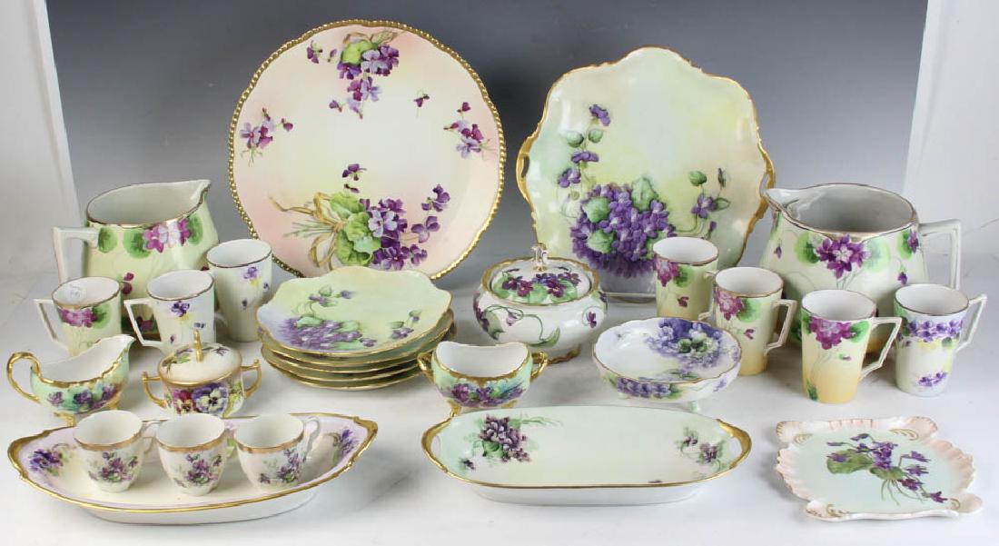 Collection Floral Decorated Porcelain Pieces: Collection of porcelain pieces decorated with purple-colored flowers, violets, pansies, etc., cider jugs, platters, mugs, cream and sugar, etc., by various makers to include Nippon, Austrian, Limoges,