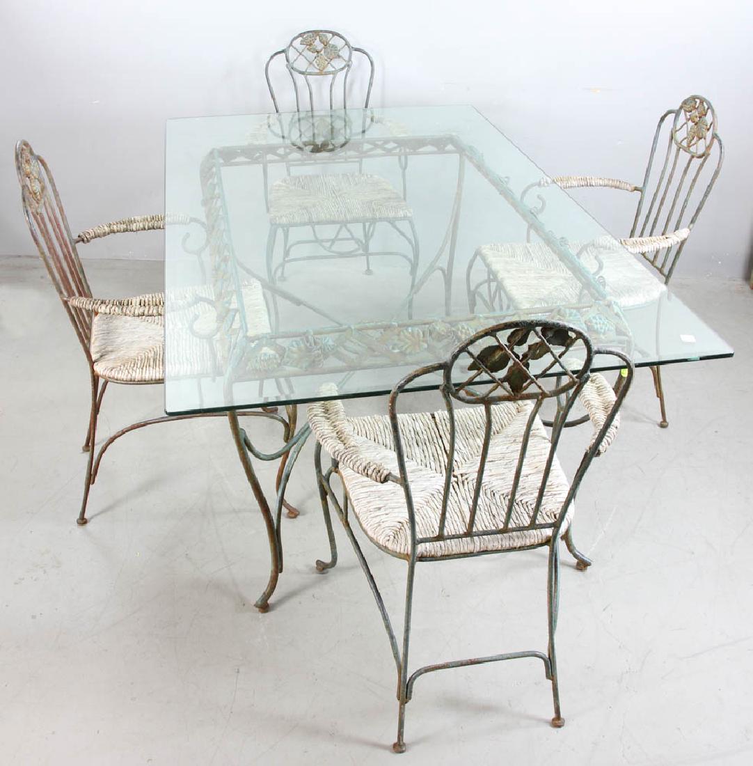 Wrought Iron Table and Chairs: Wrought iron table and four armchairs, glass top, table base measures 29" H 53" L x 34" W. Provenance: West Palm Beach, Florida estate.