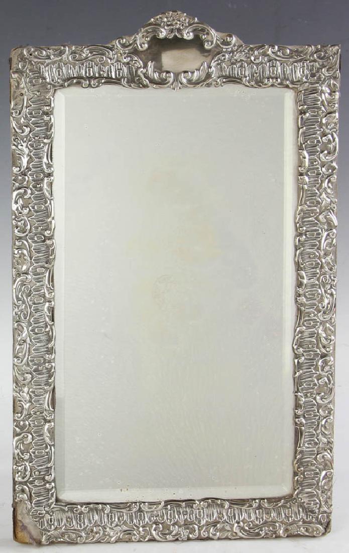 Sterling Framed Dressing Table Mirror: Dressing table mirror with beveled glass mirror and English sterling frame hallmarked for H. Mathews, Birmingham, 1906-1907, 14" H x 8 3/4" W. Provenance: Estate of Joan Potter, Martha's Vineyard, Mas