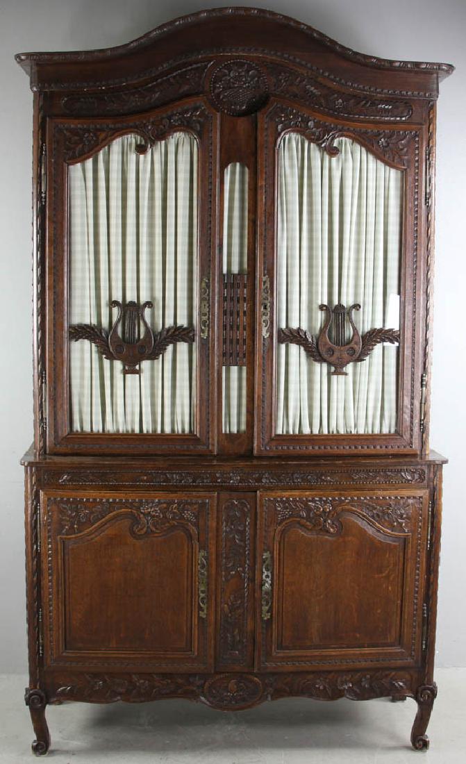 19th Century French Carved Oak Cabinet: 19th century French oak cabinet with carved basket of fruit design on crest and glass doors with carved harp detail, with keys, 92" H x 53" W x 18" D. Provenance: West Palm Beach, Florida collection.