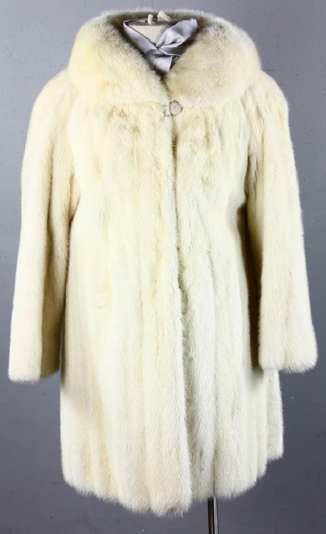 Natural Mink Stroller Coat: Natural glacial mink three quarter-length stroller coat with shaped body, set in shoulder, rounded wing band collar, 32" long and 60" sweep. Provenance: Gloucester, Massachusetts collection.