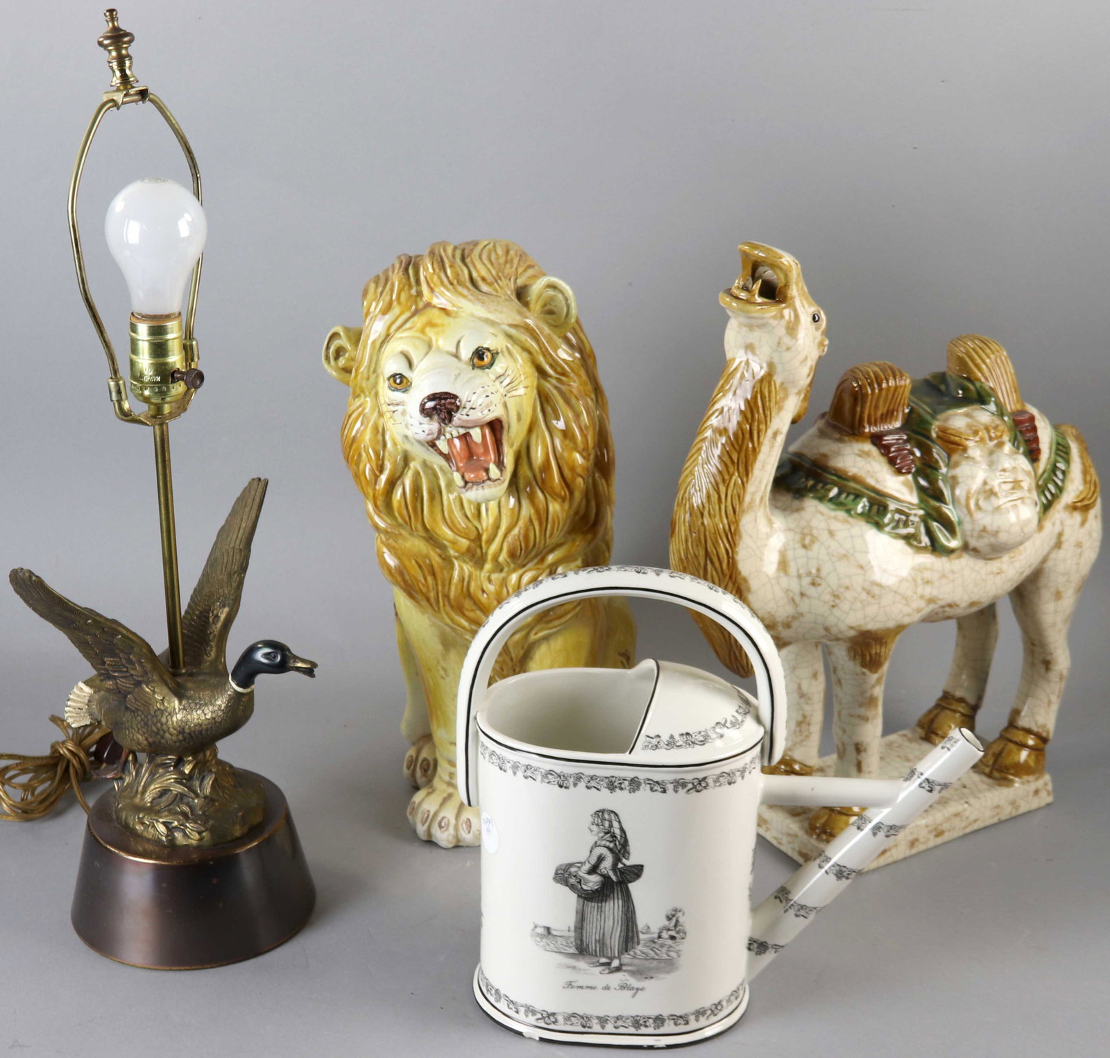 Group of Decorative Items: Group of decorative items to include figural porcelain camel, Italian ceramic lion, figural painted metal duck-motif lamp and Mottahedeh transfer decorated watering can, camel stands 18 1/4" H.