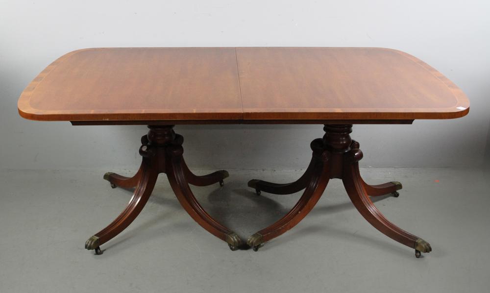 Mahogany Regency Style Dining Table: Mahogany Regency-style double pedestal dining table with inlaid top and three 16" leaves, 30" H x 67" L x 45" W.