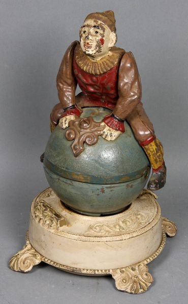 C1890 Cast Iron Mechanical Clown Bank: Circa 1890 cast iron mechanical bank "Clown on Globe" by J.E. Stevens Co., 8 3/4" x 6 7/16" (across feet). Working order; minor paint loss. Provenance: From the Estate of Dr. John & Edie Madsen of La 
