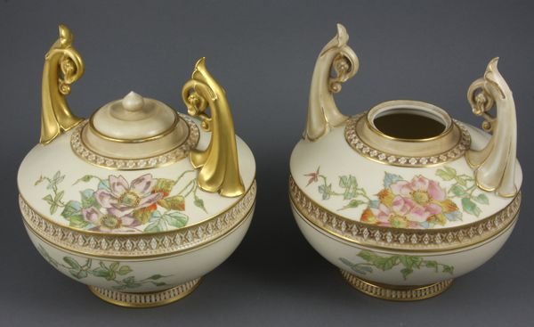 Pair of Royal Worcester Blush Ivory Vessels: Pair of late 19th Century Royal Worcester blush ivory twin-handled, covered vessels with handpainted floral decoration and gilt embellishment, 8 1/4"h. (overall), approx. 7"dia. Good condition, with e