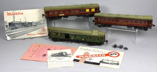 Three Marklin Schienen-Anlagen train cars: Three (3) 1930's Marklin Schienen-Anlagen train cars, with Spur O booklets and data sheets, including two (2) passenger cars and one (1) freight car, numbers 19420, 19430, and 19440, 15 1/4" l. (each)