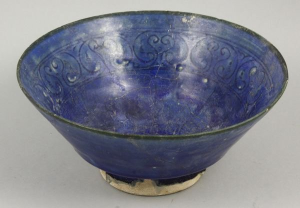 10th-13th C. Persian glazed terracotta bowl: 10th-13th Century Persian School ultramarine glazed terracotta bowl with incised petal and foliate design, 3 3/4" h. x 8 1/8" diam. Property of the late Robert O. Peterson, San Diego, CA.