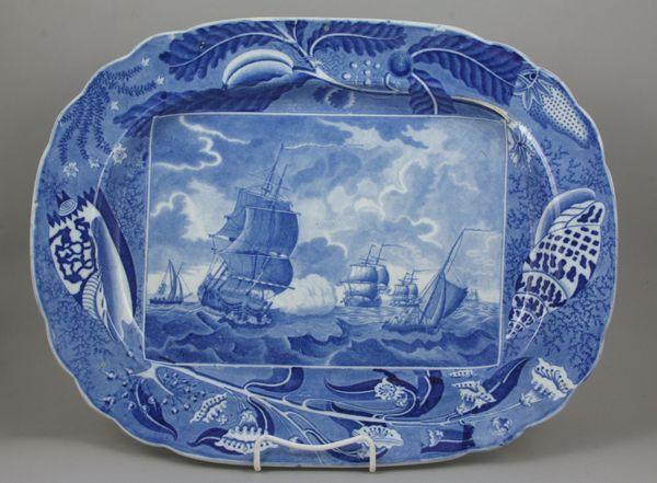 Early 19th C. English Platter: Early 19th Century transferware soft pasts blue and white platter, having a battle scene and shell and border design, attributed to Clews, 18" x 13 1/2". Minor wear on inside edge.