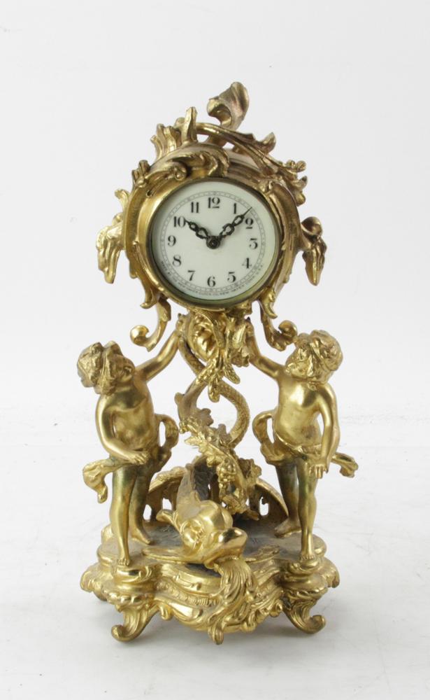 New Haven Figural Mantel Clock: New Haven figural mantel clock, gold-decorated white metal, 13" H x 5" W x 5" D. Provenance: Estate of August van der Becq, Westport, Connecticut.