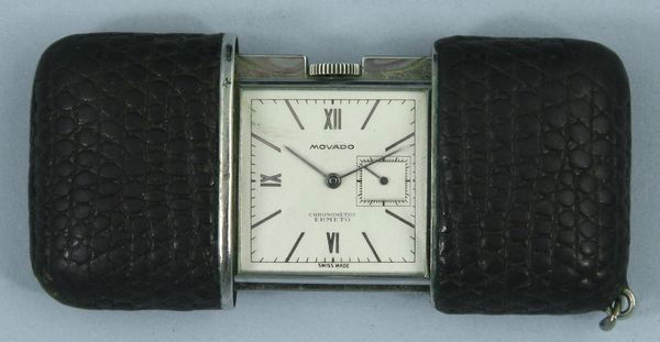 Movado Travel Watch: Movado travel watch in reptile case, "Chronometre Ermeto", 2" x 1 3/8" (closed). Undamaged, operational condition unknown. Provenance: The items offered are from the Estate of RICHARD ALFRED CHAMBERS,