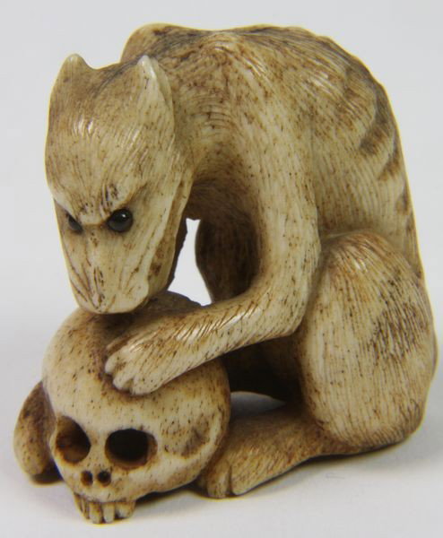 Hand-Carved Netsuke: Hand-Carved Netsuke, Japan, 19th century, of a mystical animal biting on a human skull, 1 3/4" high x 1 1/2" wide, undamaged.