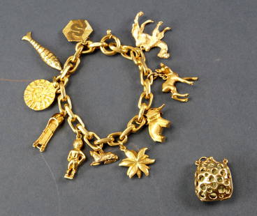 18k Yellow Gold Charm Bracelet with Charms: 18k yellow gold charm bracelet with (10) attached charms, including camel, sun symbol, bobsled, deer, cat, fish, putti, elephant, (7) marked 18k, (3) unmarked; plus one loose 14k gold charm