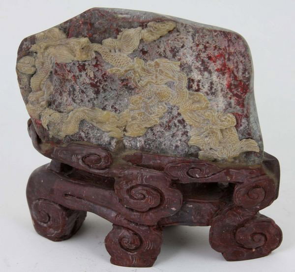 Soapstone and Chicken-Blood Stone Carving: Soapstone and Chicken-Blood Stone Carving, China, with two interlaced dragons amid clouds finely carved in relief, seated on a carved soapstone cloud-form stand, 5 1/2" high x 5 1/2" wide.