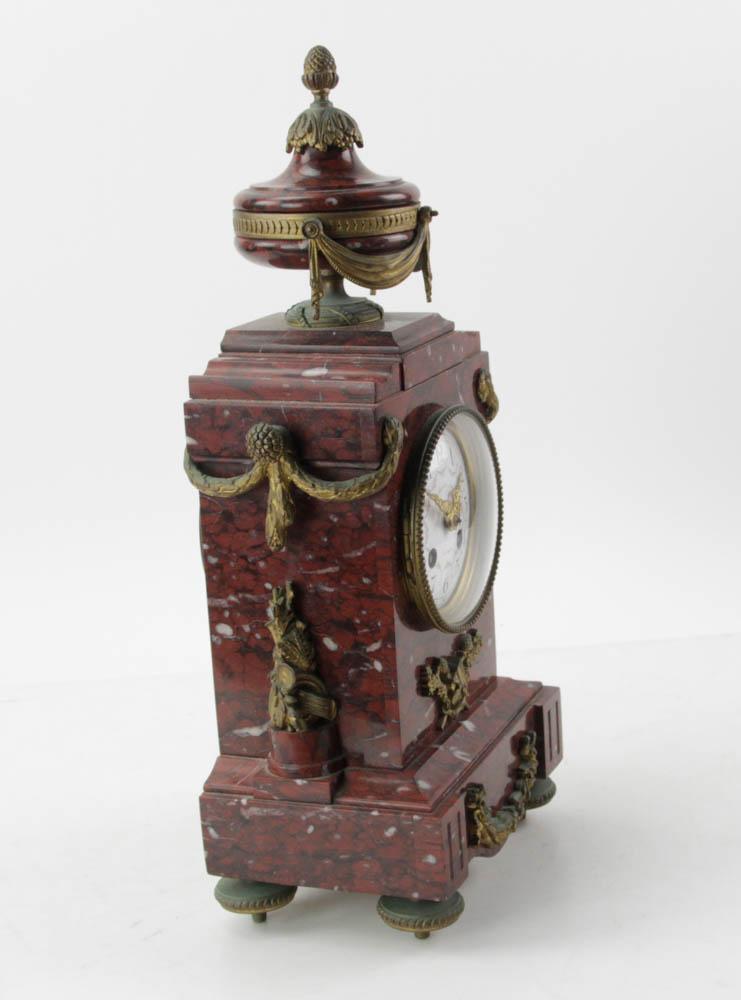 Antique French Marble Mantel Clock, Mouillard: Antique French rouge marble Louis XVI-style mantel clock, porcelain face marked G. Mouillard, ormolu bun feet, swags, pedestal urn with swags finial, 17" H x 7 1/2" W x 5" D. With key and pendulum.
