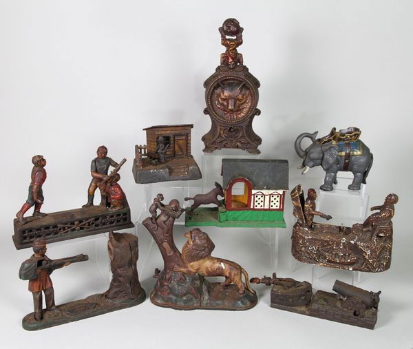 Lot of 9 Cast Iron Banks: Collection of 9 cast iron mechanical banks to include, "Uncle Remus", cat and mouse clock, "Creedmoor Bower's Series", circus elephant, "Hometown Battery", donkey and house, "U.S./Spain", lion and mon