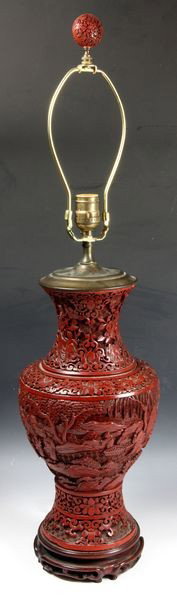 Chinese 20th C. Cinnabar Vase-Lamp: Cinnabar vase, China, early 20th century, the bulbous body carved with figures in a landscape, the neck decorated with scrolling lotus flowers, converted to a lamp, on wood base.