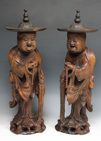 Pair of Chinese 19th C. Wood Carved Figures: Pair of carved wood monks, China, 19th century, each holding prayer beads in one hand and with a horsehair whip in the other, mirror images, 14 1/2"h.