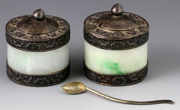 20th C. Chinese Jadeite Salt and Pepper Cellars: Salt and pepper cellars, China, early 20th century, with silver lids and bases embossed with flowers, marked "China Silver" on base, together with a tiny silver spoon, jadeite, 1 1/2"h x 1 1/4"dia.