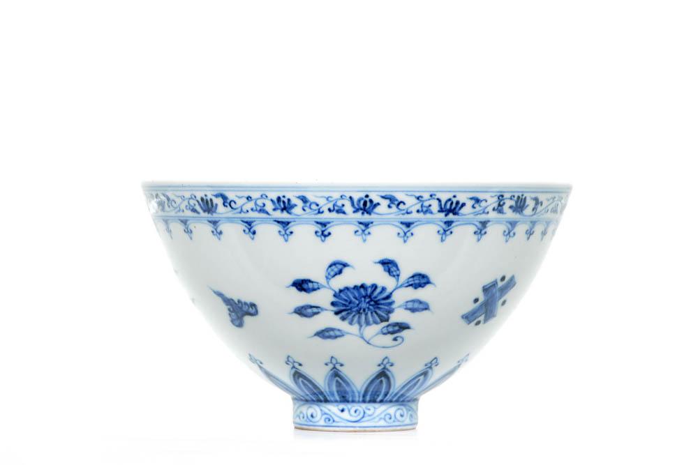 A Rare Chinese Blue and White Bowl: Finely potted bowl with deep sides that rise from the small foot ring, decorated with alternating clusters of flower blossoms and Buddhism emblems, all between band of leafy lotus scrolls and upright 