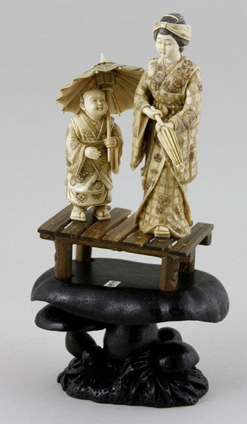Japanese Ivory Figurines: Figure of a Woman and Child, Japan, ivory, both wearing traditional robes and carrying umbrellas, on carved wood stand, 5".