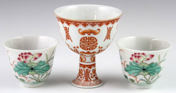 Chinese 19th C. Wine Cups: Three Wine Cups, China, 19th century, including a pair of famlle rose teacups with lotus flowers, and one red glazed stem cup decorated with bats and the longevity character, biggest 3 1/4"h x 2 7/8"w