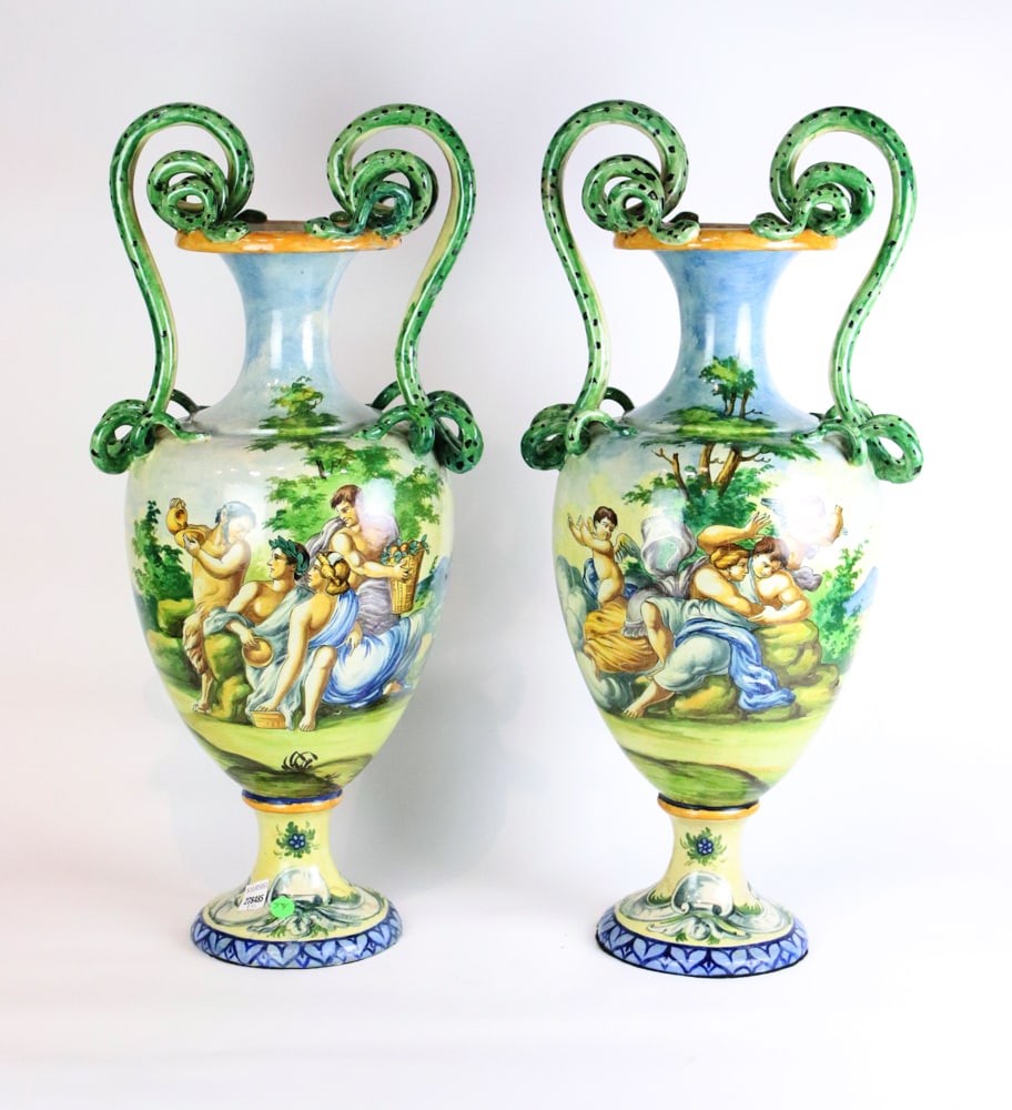 Pair of 19thC Italian Majolica Urns: Pair of 19th century Italian Majolica urns, pastoral scenes with Pan, one with putti, double snake handles, 36" H x 12" W x 10" D. Good condition; repair to the base of one. Provenance: Estate of Robe