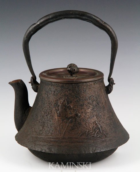 19th C. Japanese Teapot: Cast iron teapot, Japan, 19th century with a bronze lid, decorated with a village scene in relief, 8 3/4" x 7". Minor cracks and chips.