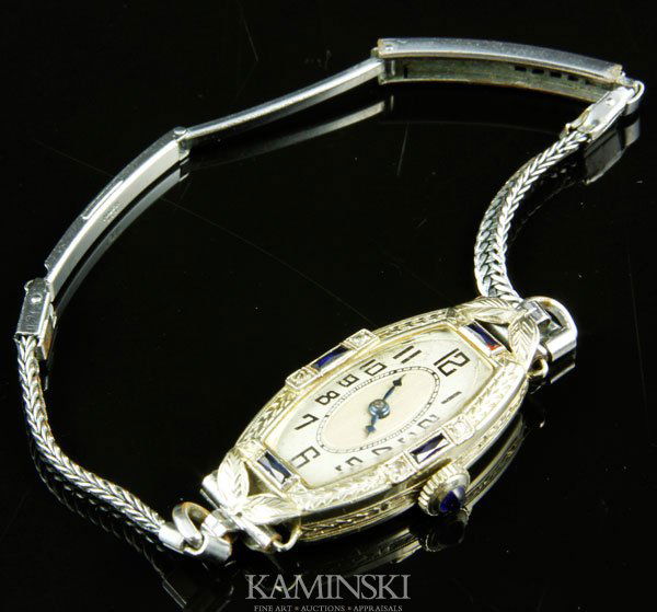 18K Gold Ladies Watch: 18K white gold ladies watch, case marked S Bruner inside, movement is Boston Watch Co., Swiss, 17 jewels, oblong case includes small sapphires and diamond chips, plus cabochon sapphire on stem, approx