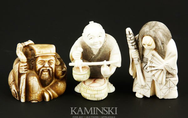 3 Japanese Ivory Netsukes: Three carved netsukes, Japan, ivory, including one long haired woman with a movable face, holding an umbrella and fan, mark on base, 2" h; one merchant holding a scale, mark on base, 2" h; and one sea