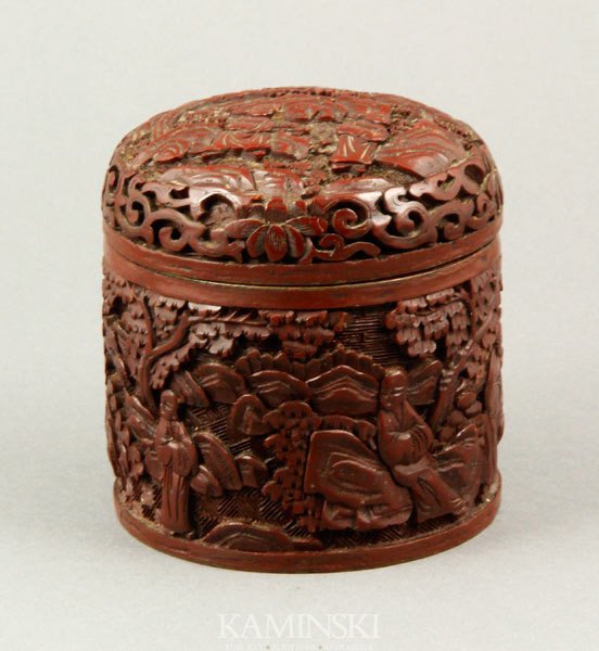 Chinese Carved Cinnabar Box: Cinnabar box, China, cylindrical form carved with figures in a rocky landscape, 3 3/8" h x 3 1/8".