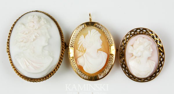 3 10K Gold Cameos: Collection of three cameos in 10K gold frames, to include: shell, 1 1/4"h x 1"w; angel skin coral, 1 1/2"h x 1 1/4"w; angel skin coral, 1 1/8"h x 1"w.