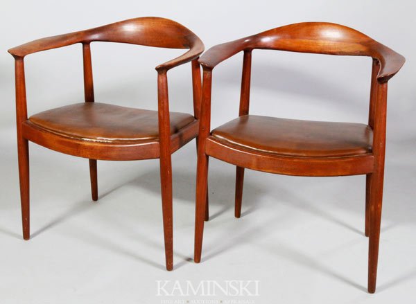 Pair Hans Wegner Armchairs: Pair of Hans Wegner armchairs, "the chair", or "the round chair", red-brown finish with brown leather seats, circa late 1950s/ early 1960s, likely early contract furniture, they are not marked save a