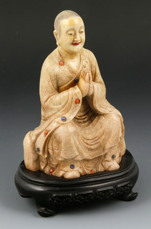 Chinese Carved Soapstone: Chinese carved soapstone of seated Lohan figure with inlaid stones and wood stand, 5 1/2" x 3 1/2".
